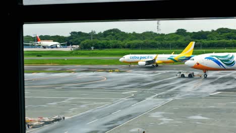 Ein-A320-Der-Cebu-Pacific-Air-Rollt-Vor-Dem-Start-Zur-Landebahn,-Während-Ein-Großraumflugzeug-A330-Zu-Seinem-Zugewiesenen-Parkplatz-Geschleppt-Wird