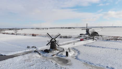 Typical-Dutch-winter-snow-covering-traditional-windmills,-aerial-landscape
