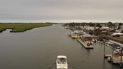 An-aerial-view-of-a-small-fishing-boat-sailing-in-a-marsh-in-Freeport,-NY