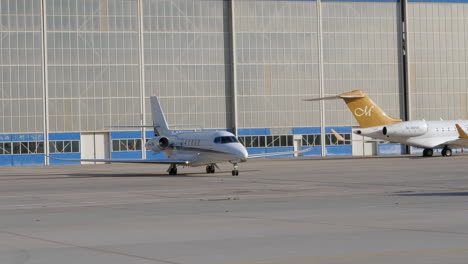 Jet-Privado-En-La-Plataforma-Del-Aeropuerto-Siguiendo-Al-Automóvil-Frente-Al-Edificio-Del-Hangar
