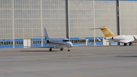 Private-jet-on-airport-apron-following-car-in-front-of-hangar-building