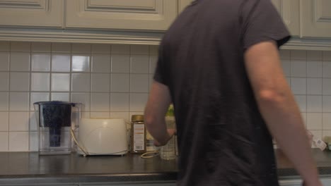 Man-places-water-bottle-on-kitchen-counter-with-prepared-lunchbox