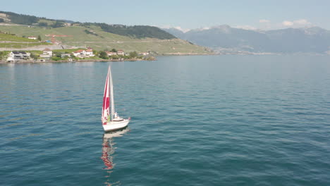 Aerial-orbit-of-small-sail-boat-on-a-vast,-blue-lake