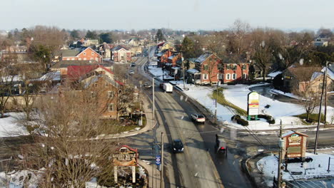 AERIAL-Small-USA-Country-Town-Street-With-Traffic-During-Snowstorm