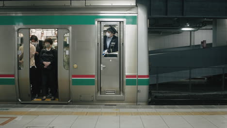 Pasajeros-Y-Conductor-De-Tren-Con-Máscaras-Dentro-De-Un-Tren-En-La-Estación-Con-Cierre-De-Puerta-En-Sendai,-Japón