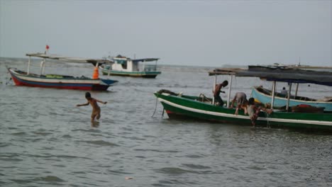 Mehrere-Kinder-Spielten-In-Der-Nähe-Des-Fischerbootes,-Das-Am-Strand-Lag