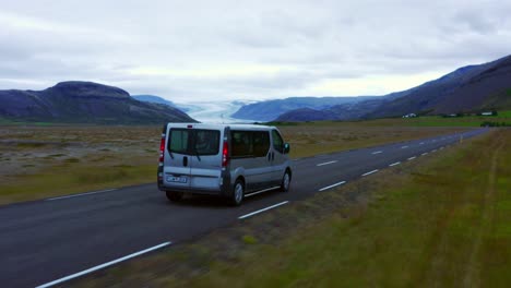 Campervan-Driving-On-Asphalt-Road-In-Hoffell,-Iceland-With-View-Of-Hoffellsjokull-Glacier-In-Distance
