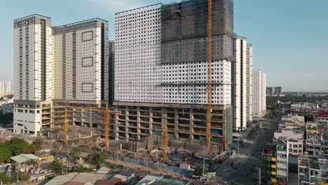 Drone-flying-backwards-shows-a-building-under-construction-with-clear-sky-line