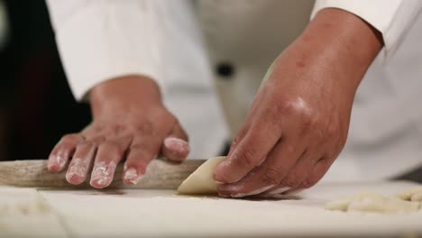 Hand-rolling-the-edge-of-Chinese-dumplings-with-a-traditional-wooden-rolling-pin