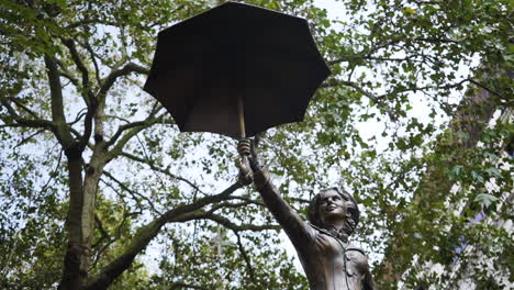 Una-Estatua-De-Mary-Poppins-En-Leicester-Square,-Londres-Está-Rodeada-De-árboles-En-El-Famoso-Extremo-Oeste-De-La-Ciudad