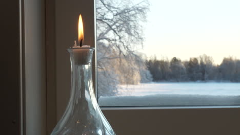 Innenansicht-Einer-Kerze,-Die-Im-Fenster-Brennt,-Mit-Verschneiter-Winterlandschaft-Draußen