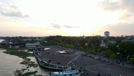 Tourist-destination-spot-near-Musi-river-in-city-of-Palembang,-aerial-fly-backward-view