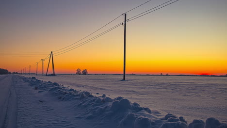 Time-lapse-shot-of-snowy-winter-field-and-orange-and-blue-colored-sky-after-sunset---Blue-hour-in-rural-landscape-in-the-evening