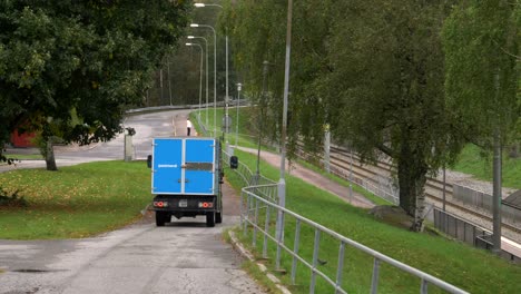 Postnord-Electric-mail-van-transport-driving-through-a-road