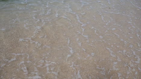 Omicron-Schriftzug-Auf-Weißem-Strandsand,-Der-Von-Wellen-Gelöscht-Wird