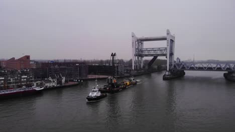 En-Avant-9-Tugboat-Pulling-Barge-With-Liebherr-Crane-Along-Oude-Maas-Through-Spoorbrug-Railway-Bridge
