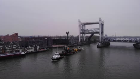 En-Avant-9-Schlepper-Zieht-Lastkahn-Mit-Liebherr-Kran-Entlang-Der-Oude-Maas-Durch-Die-Spoorbrug-Eisenbahnbrücke