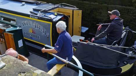 Helmsmen-sitting-at-the-stern-of-two-narrowboats-navigating-Bunbury-canal-lock-system