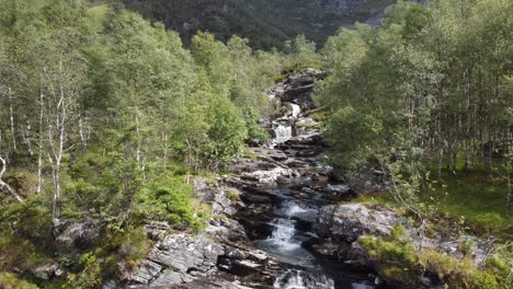 Flying-very-close-to-crispy-clean-river-stream-in-between-birch-trees-in-Norway-mountains---Leiro-Eidslandet-Norway-forward-moving-aerial-in-complete-wilderness