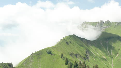 Atemberaubende-Luftaufnahme-Von-Wolken,-Die-Mit-Grünen-Berggipfeln-Kollidieren