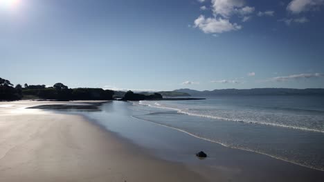 Calm-waves-over-the-smooth-beach-of-Tawharanui-Regional-Park,-New-Zealand