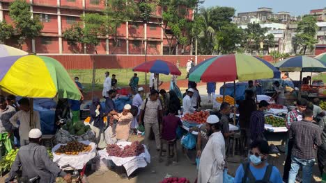Vista-De-Derecha-A-Izquierda-De-Un-Concurrido-Mercado-De-Frutas-Al-Borde-De-La-Carretera-Que-Vende-Naranjas,-Uvas,-Guayaba,-Plátano,-Granada-En-Un-Hermoso-Día-Soleado-En-Dhaka,-Bangladesh