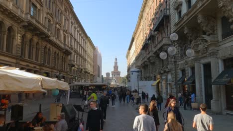 Importante-Calle-Peatonal-Vía-Dante-En-Milán-Con-Gente-Paseando-Y-Comprando-Con-El-Castillo-Sforza-En-El-Fondo,-Italia