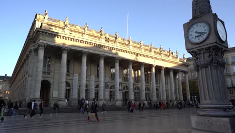 Opera-house-plaza-with-the-big-clock-column-and-trolley-car-tracks-as-people-walk-by,-Left-pan-shot