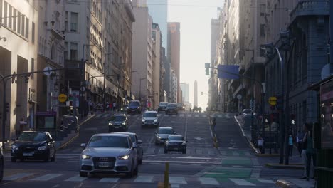 Off-work-rush-hours-traffic-shot-on-the-dull-busy-junction-of-downtown-Buenos-Aires-between-corrientes-and-leandro-n-alem-avenue-with-monumental-obelisk-in-far-distance-background