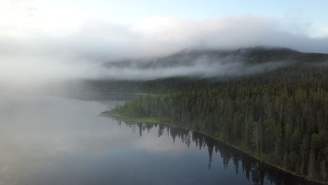 Aerial-view-of-lake-and-forest-filled-with-mist-in-Lapland-Finland