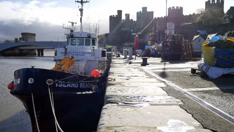 Island-reach-fishing-trawler-boat-anchored-on-Conwy-castle-harbour-low-tide-dolly-left-shot