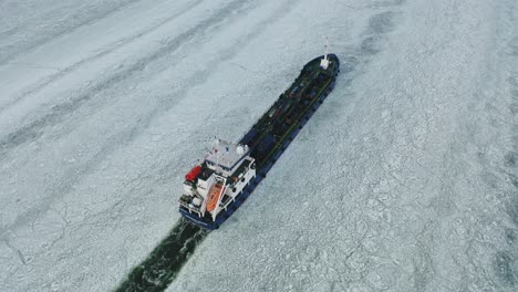 Top-down-tracking-aerial-view-of-oil-and-chemical-tanker-CRYSTALWATER-call-sign-ESLI,-moving-ahead-in-ice-covered-Finnish-archipelago