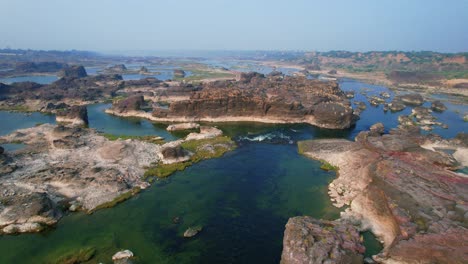 Aerial-backward-moving-shot-of-Beautiful-natural-scenery-of-Narmada-river-located-in-Gujrat,-India-in-Southeast-Asia-surrounded-by-tropical-green-forest-in-the-background