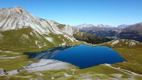 Rims-Lake,-blue-crystal-clear-water-in-the-high-mountain-scenery-of-the-swiss-alps,-aerial-shot