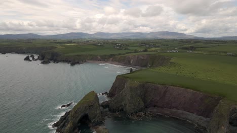 Drone-shot-showing-of-a-large-landscape-in-Ireland-with-a-beach-and-sea-cliffs