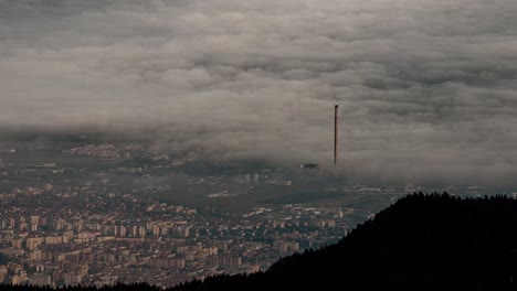 Top-of-the-mountain-view-with-fog-waves-over-a-big-city