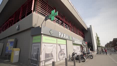 Pharmacy-and-Convenience-store-with-modern-digital-sign-and-mopeds-parked-in-front,-Rotating-slow-motion-shot