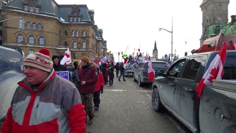 View-of-parked-pickup-trucks-and-protesters-walking-down-the-street,-Freedom-convoy-protest-in-Ottawa,-Canada