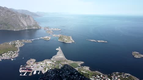 Flying-at-Reinbringen,-Lofoten-overlooking-the-islands-of-Reine-and-the-ocean,-as-well-as-the-mountain-chains-of-the-Lofoten-islands-in-the-background