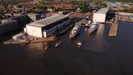 Luftaufnahme-Von-Schleppern,-Die-Der-Luxusyacht-Helfen,-Am-Yachthafen-Der-Oceanco-Werft-Anzudocken