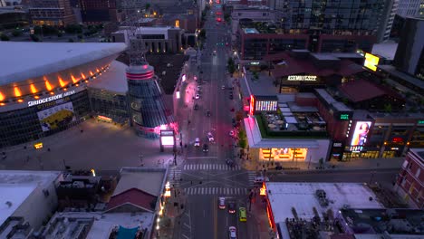 Aerial-view-over-the-illuminated-Broadway-street,-dusk-in-Nashville,-USA---reverse,-drone-shot