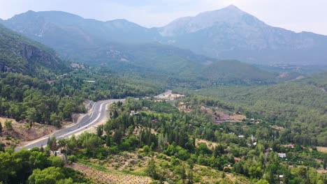 Drone-Aéreo-Con-Vistas-A-Las-Montañas-Taurus-En-Antalya-Turquía-Mientras-Una-Carretera-Pasa-Por-El-Valle-Verde-En-Un-Día-Soleado-De-Verano