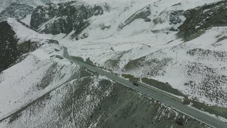 Aerial-View-Of-Parked-SUV-On-Desolate-Winter-Road-Beside-Snow-Covered-Landscape-In-Upper-Hunza