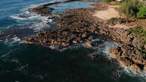 Aerial-tilt-up-shot-flying-low-over-snorkelers-and-swimmers-in-Shark-Cove-along-O'ahu's-North-Shore-in-Hawaii