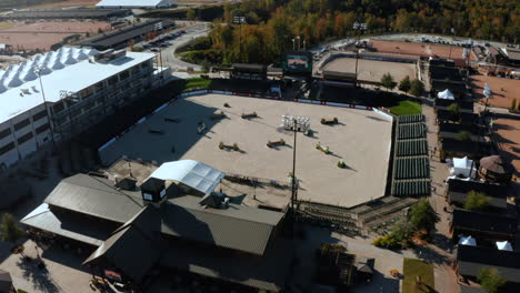 Aerial-circling-around-an-outdoor-equestrian-center-as-a-horse-and-rider-run-the-jumping-course