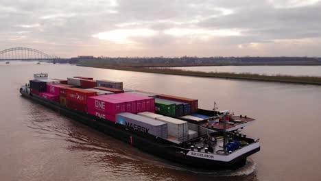 Luftaufnahme-Eines-Excelsior-Frachtschiffs-Und-Eines-Lastkahns,-Die-Frachtcontainer-Auf-Dem-Fluss-Noord-Transportieren,-Mit-Crezeepolder-Im-Hintergrund