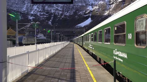 Flamsbanen-train-with-rail-cars-waiting-on-platform---Green-traditional-historic-train-ride-from-Flam-Norway---Backward-moving-clip-from-station