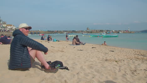 Man-Tourist-Sitting-and-Relaxing-On-The-Beach-Near-St