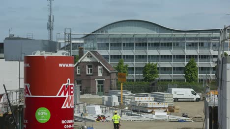 Steady-frame-time-lapse-showing-work-being-done-on-construction-site-with-workers-walking-among-raw-material-and-operating-heavy-machinery-around-initial-phases-of-the-building-process