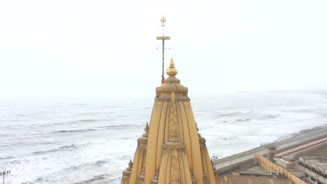 Aerial-drone-rotating-shot-of-Somnath-mandir-with-cityscape-and-sea-in-the-background